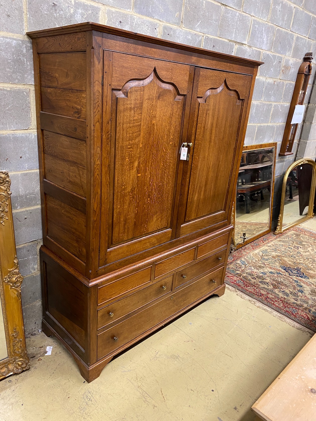 An 18th century and later panelled oak hanging cupboard fitted drawers, width 138cms, depth 56cms, height 186cms.